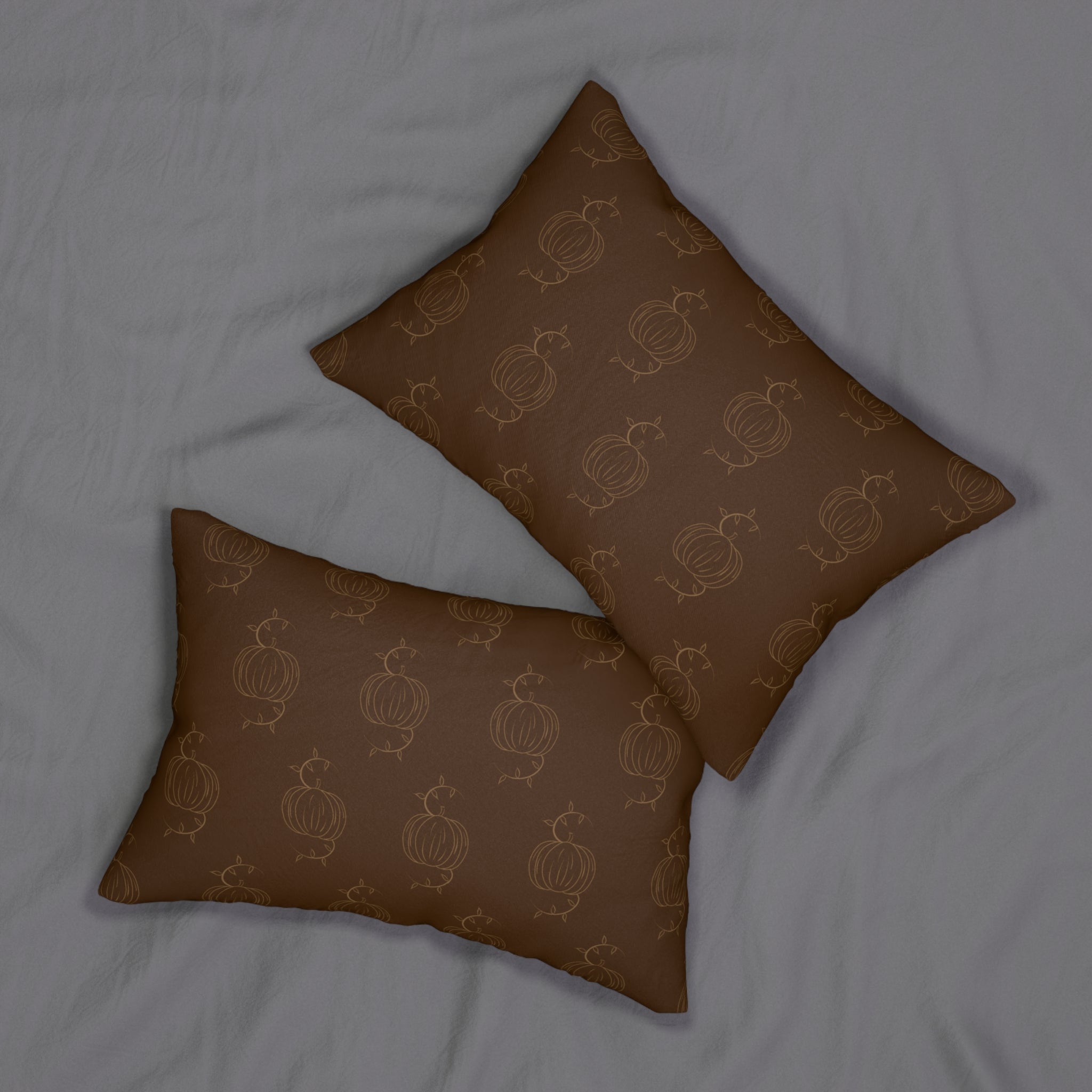 Two brown lumbar pillows with tan pumpkin pattern, stacked on a fabric surface