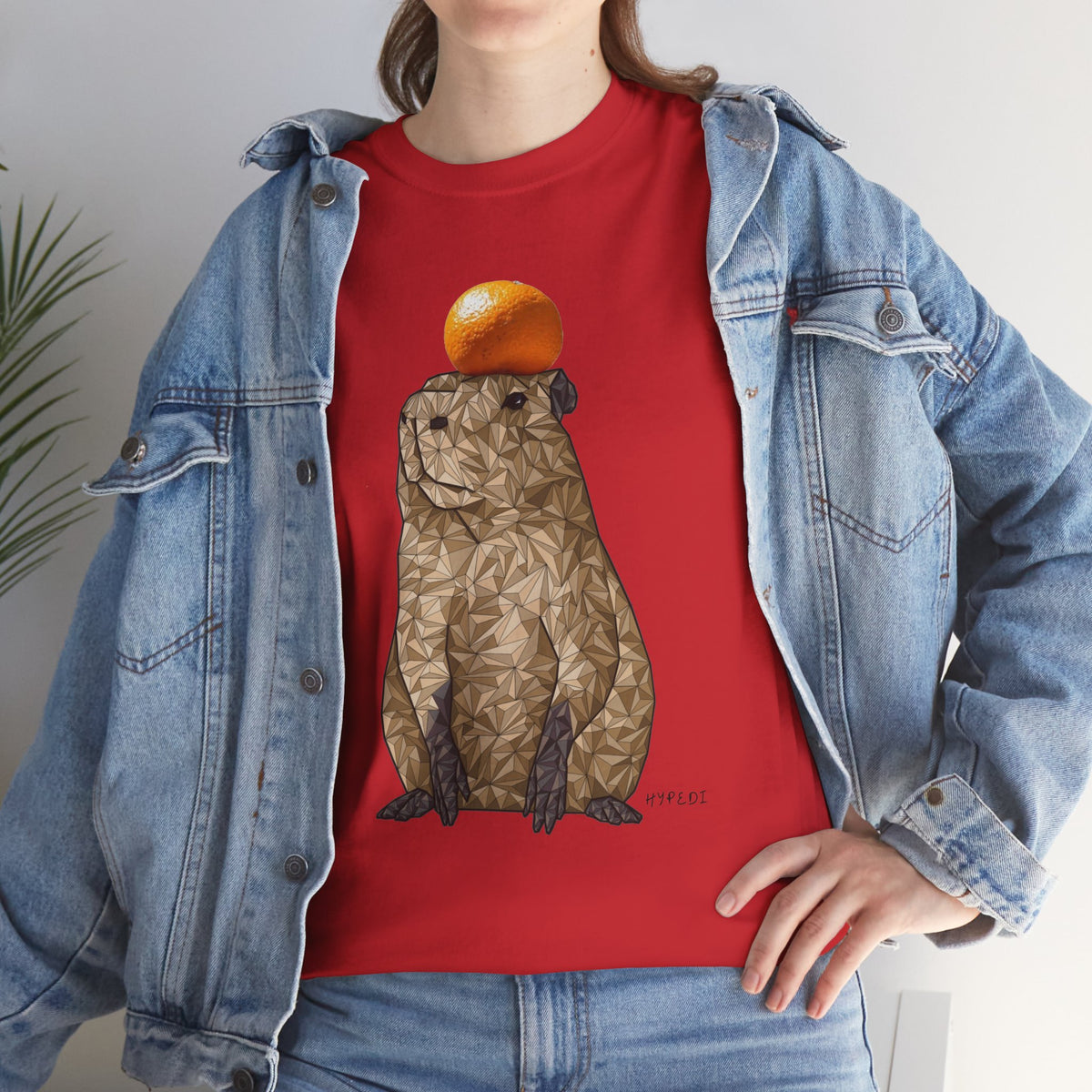Red unisex T-shirt with capybara graphic holding an orange on the front