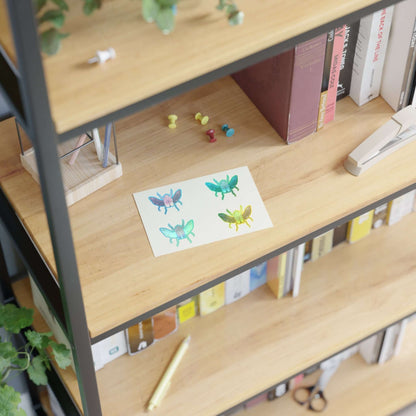 Die-cut sticker sheet with four colorful beetle illustrations on white paper