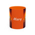 Orange coffee mug with “Mary” script and origami crane artwork on black side panels
