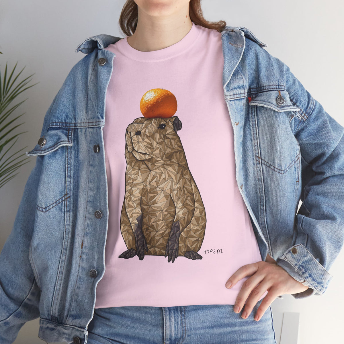 Pink unisex T-shirt with capybara graphic holding an orange on the front