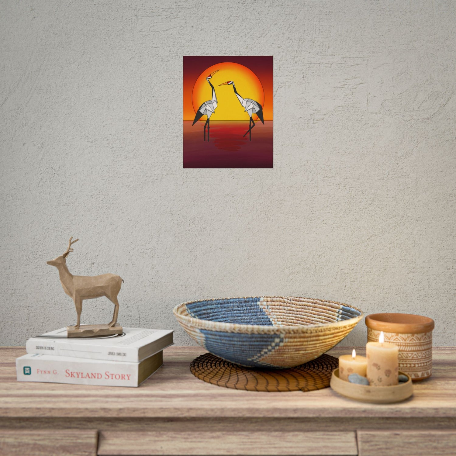 Small sunset origami crane poster on a wall above a wooden console table