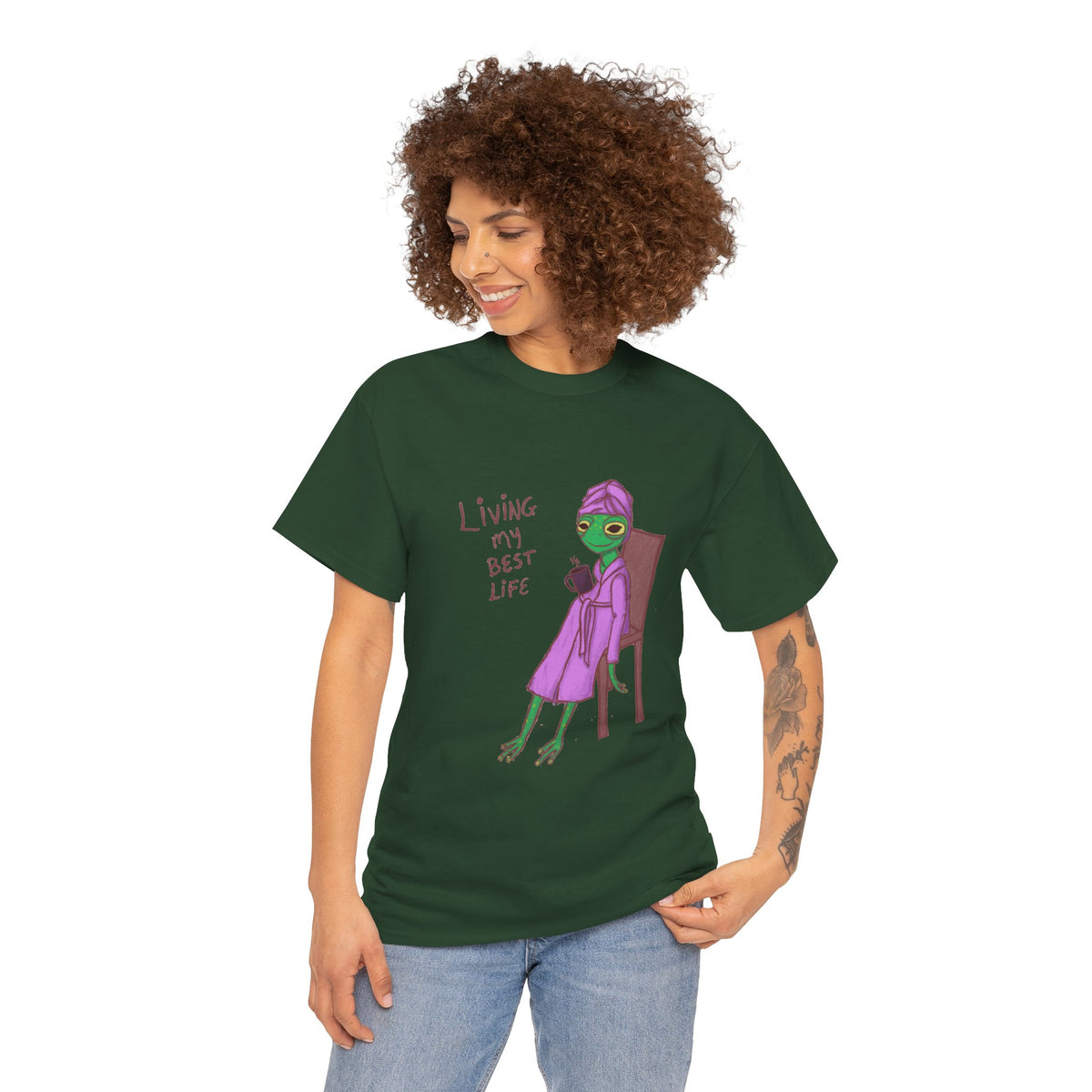 Dark green short-sleeve graphic t-shirt worn by woman, purple character and red text