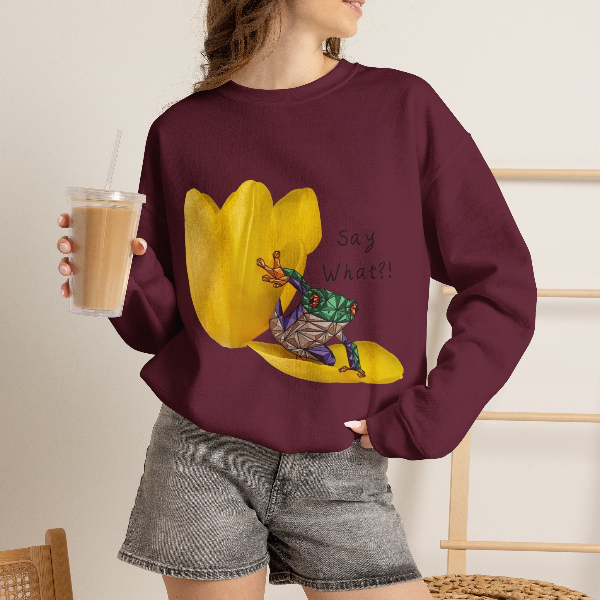 Maroon crewneck sweatshirt on model with yellow tulip frog graphic and “Say What?!”