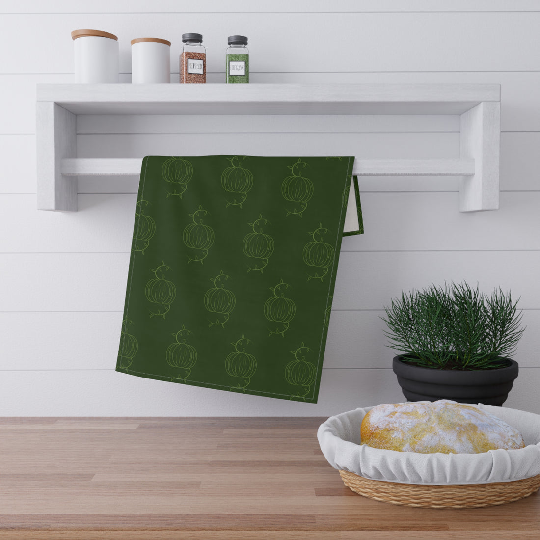 Green tea towel with repeating pumpkin line pattern, folded rectangle