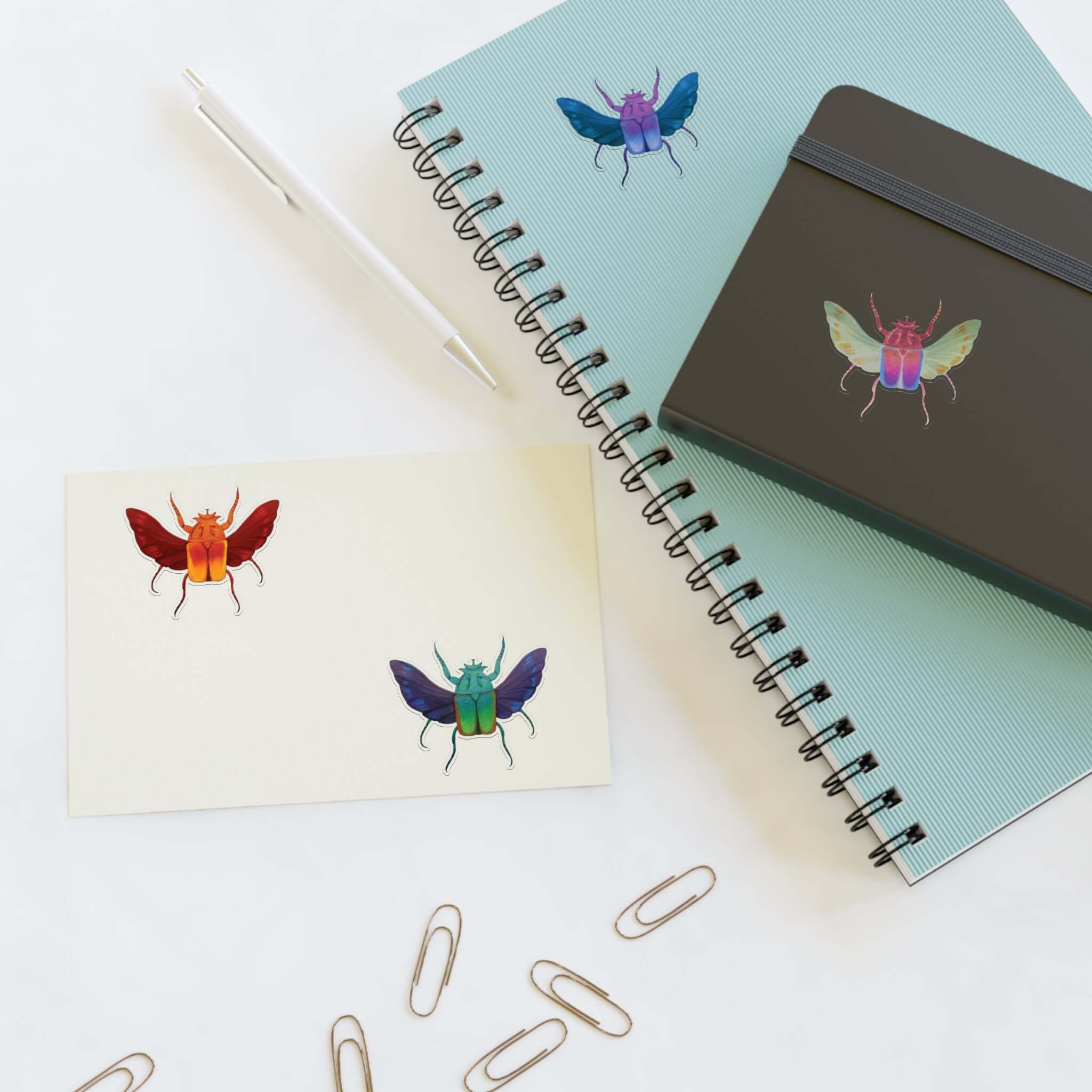 Die-cut sticker sheet with four colorful beetle designs on white paper