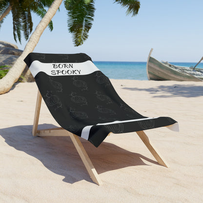 Black towel draped on wooden beach chair with white stripe, &