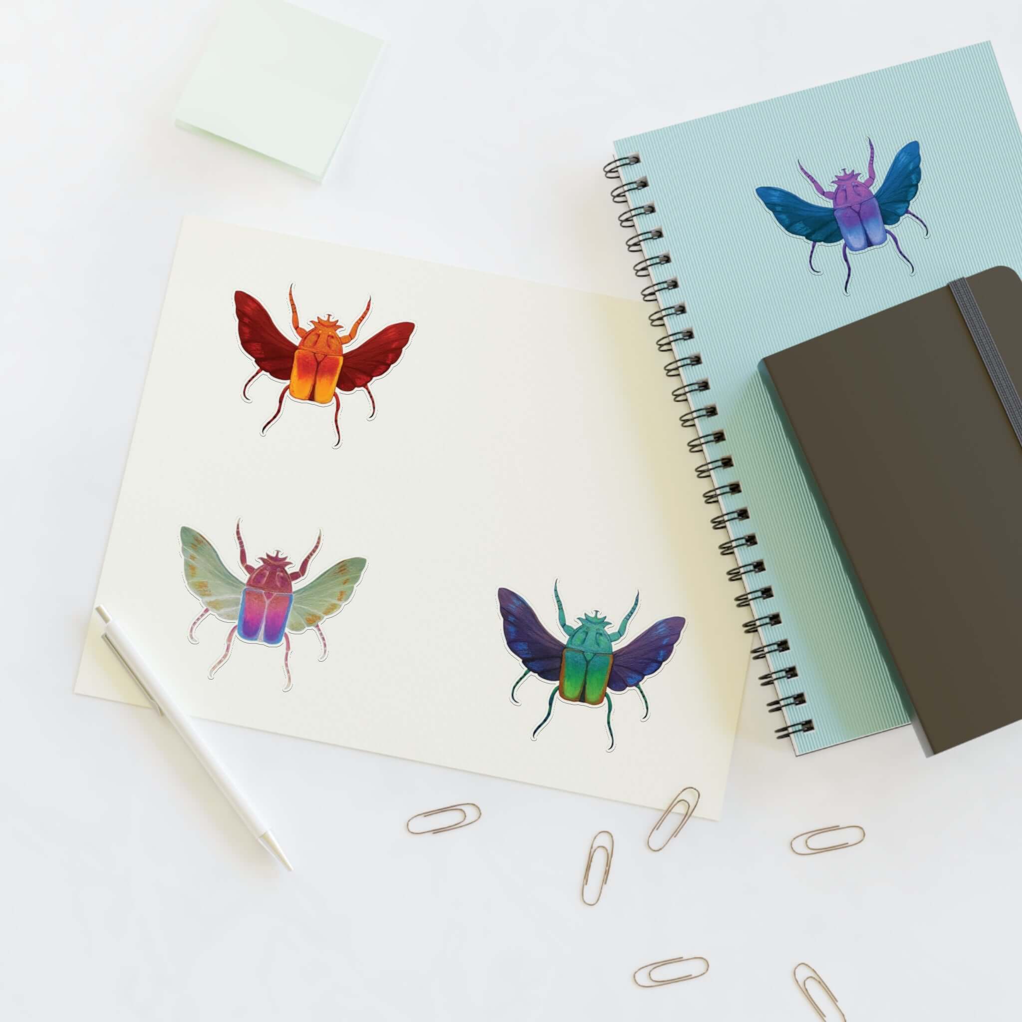 Die-cut sticker sheet with four colorful beetle designs on white paper