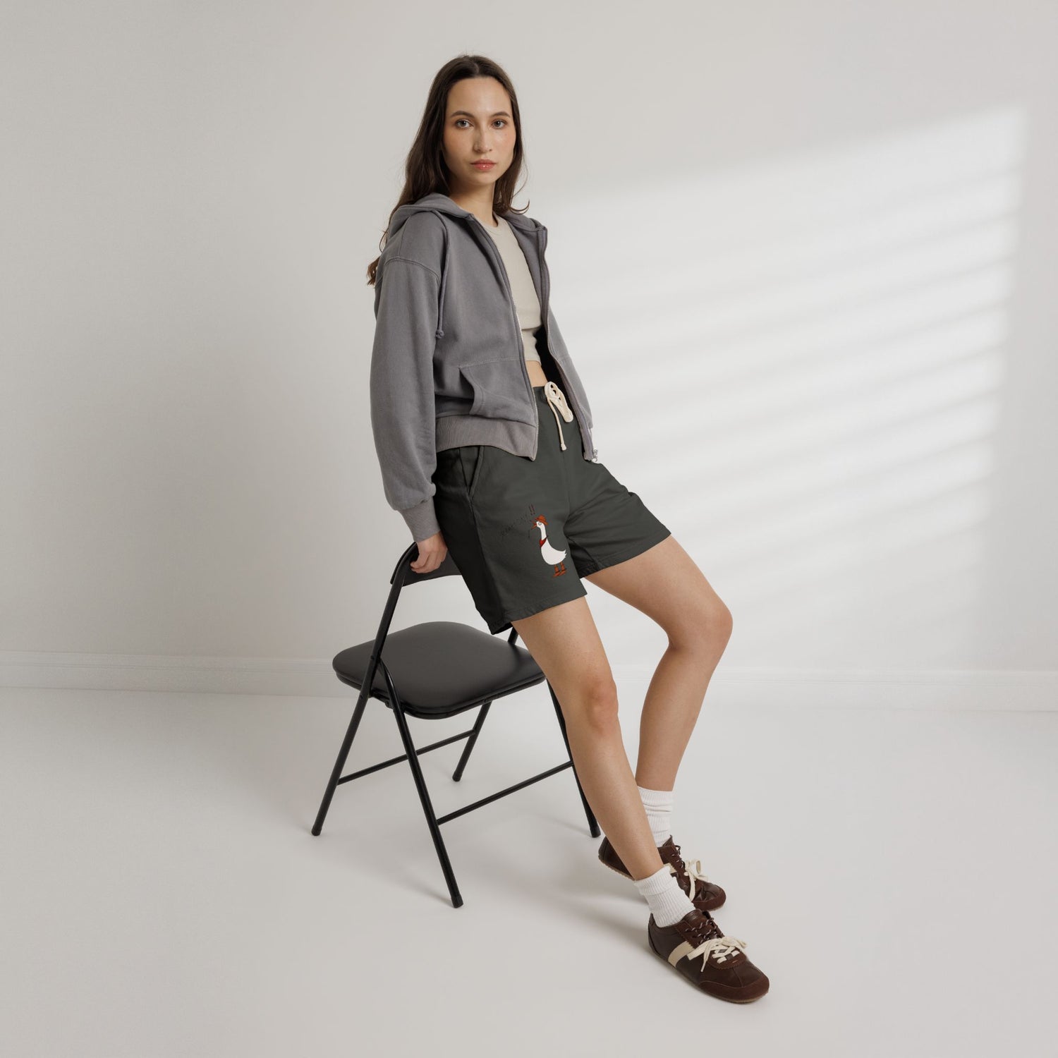 Dark gray sweat shorts with drawstring and small goose graphic, worn by model