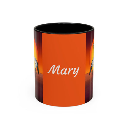 Orange coffee mug with black rim, “Mary” script and origami crane artwork