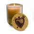 Amber soy candle with lit wick and round engraved wooden lid with heart design.