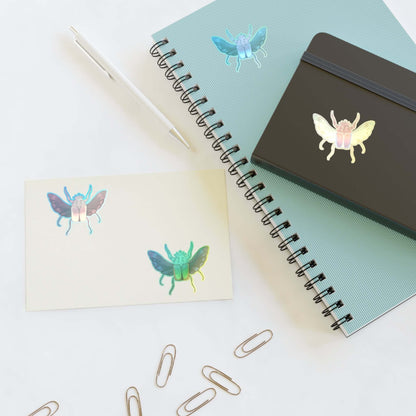 Holographic die-cut sticker sheet with butterfly decals on a white card near a notebook