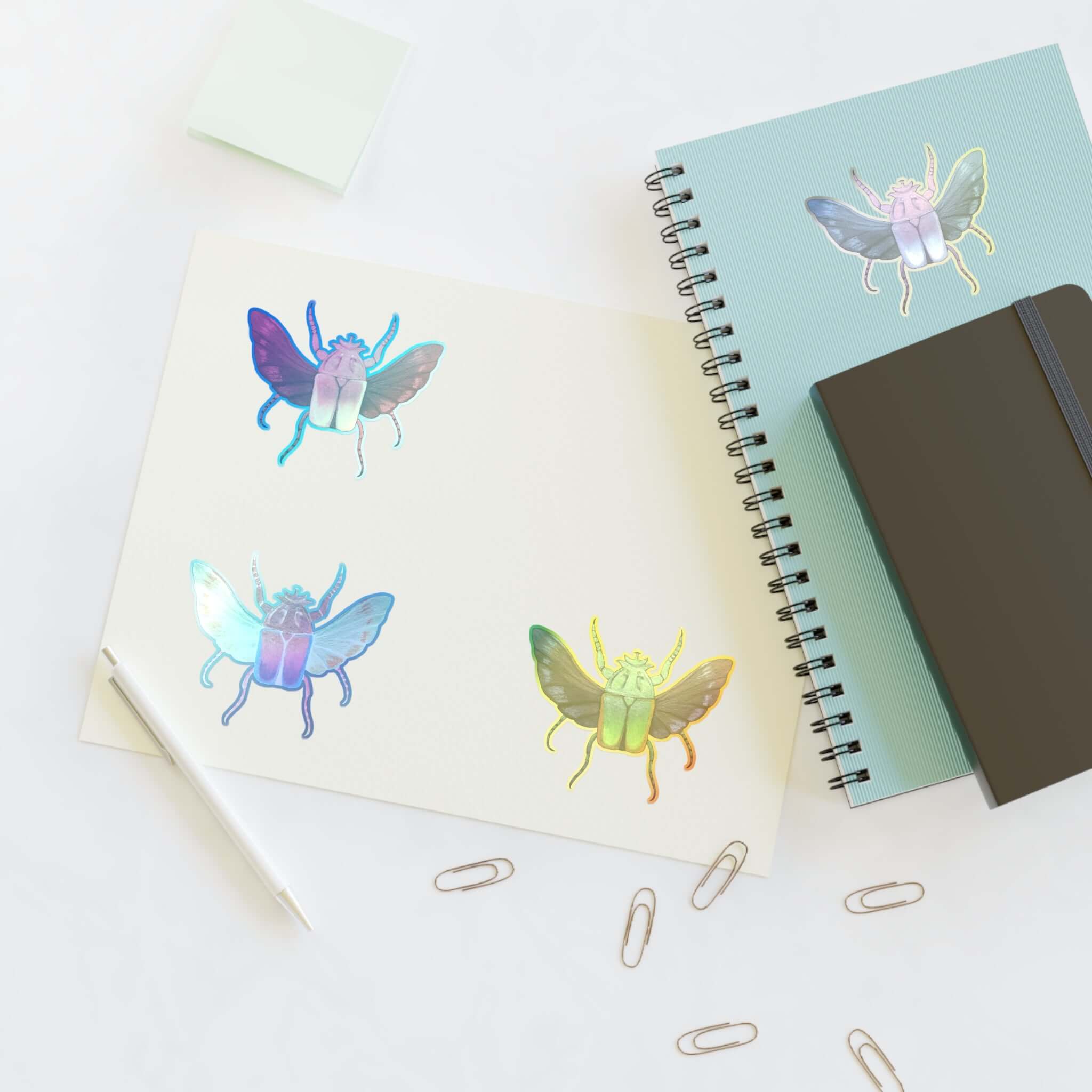 Holographic die-cut sticker sheet with four iridescent butterfly decals near binder rings