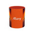 Orange coffee mug with black accents, “Mary” text and origami crane graphic on the sides