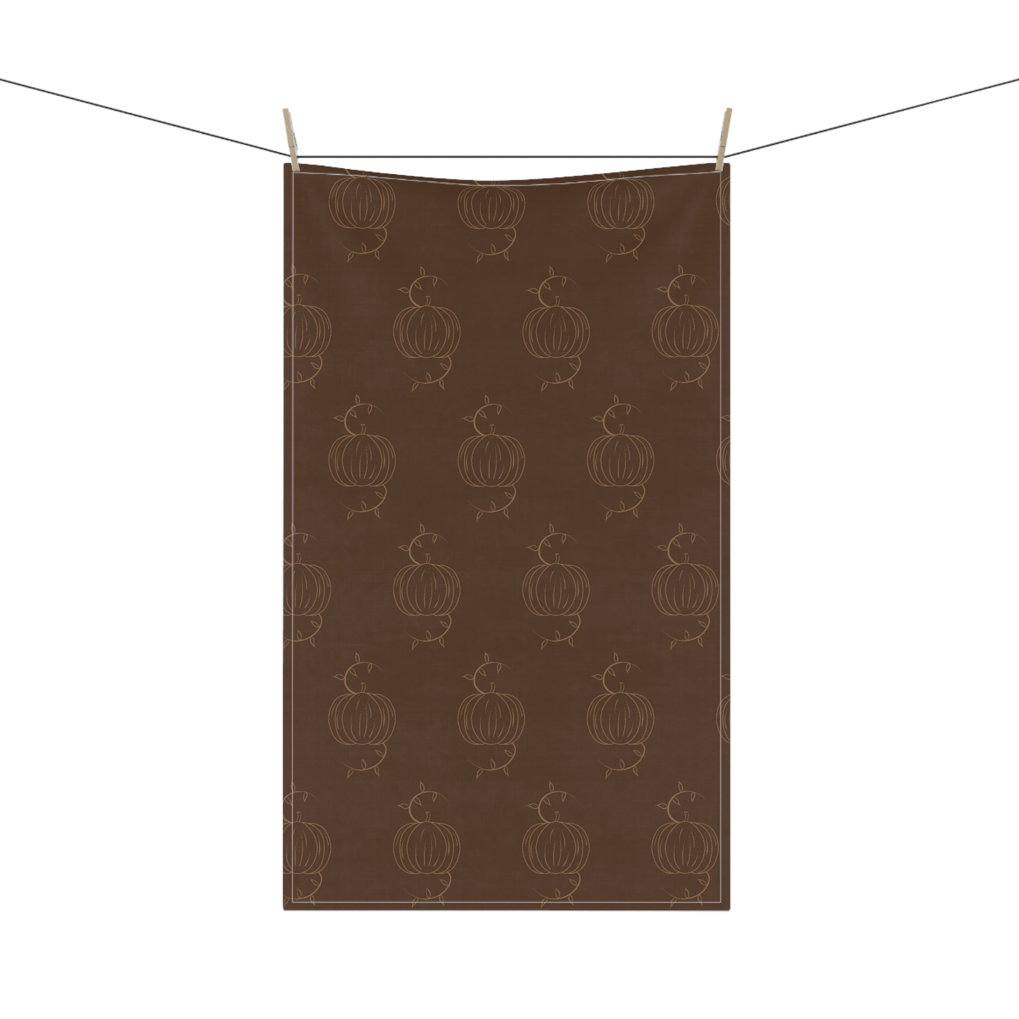 Brown tea towel with repeating pumpkin line pattern, hanging from two clips