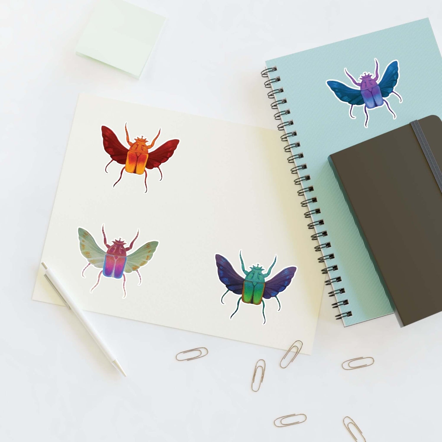 Die-cut sticker sheet with four colorful beetle designs on white paper