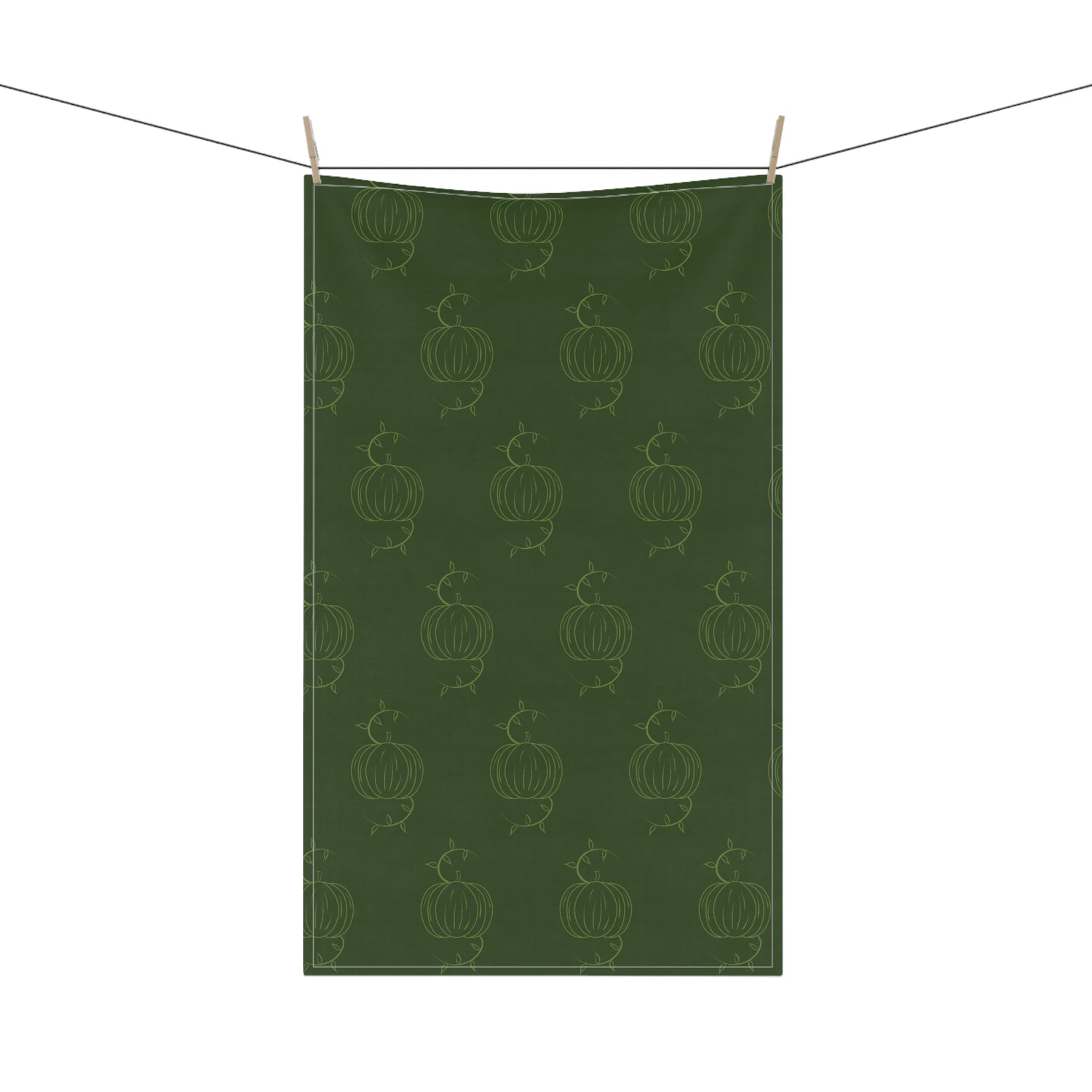 Hanging green tea towel with repeating pumpkin line pattern and clothespins