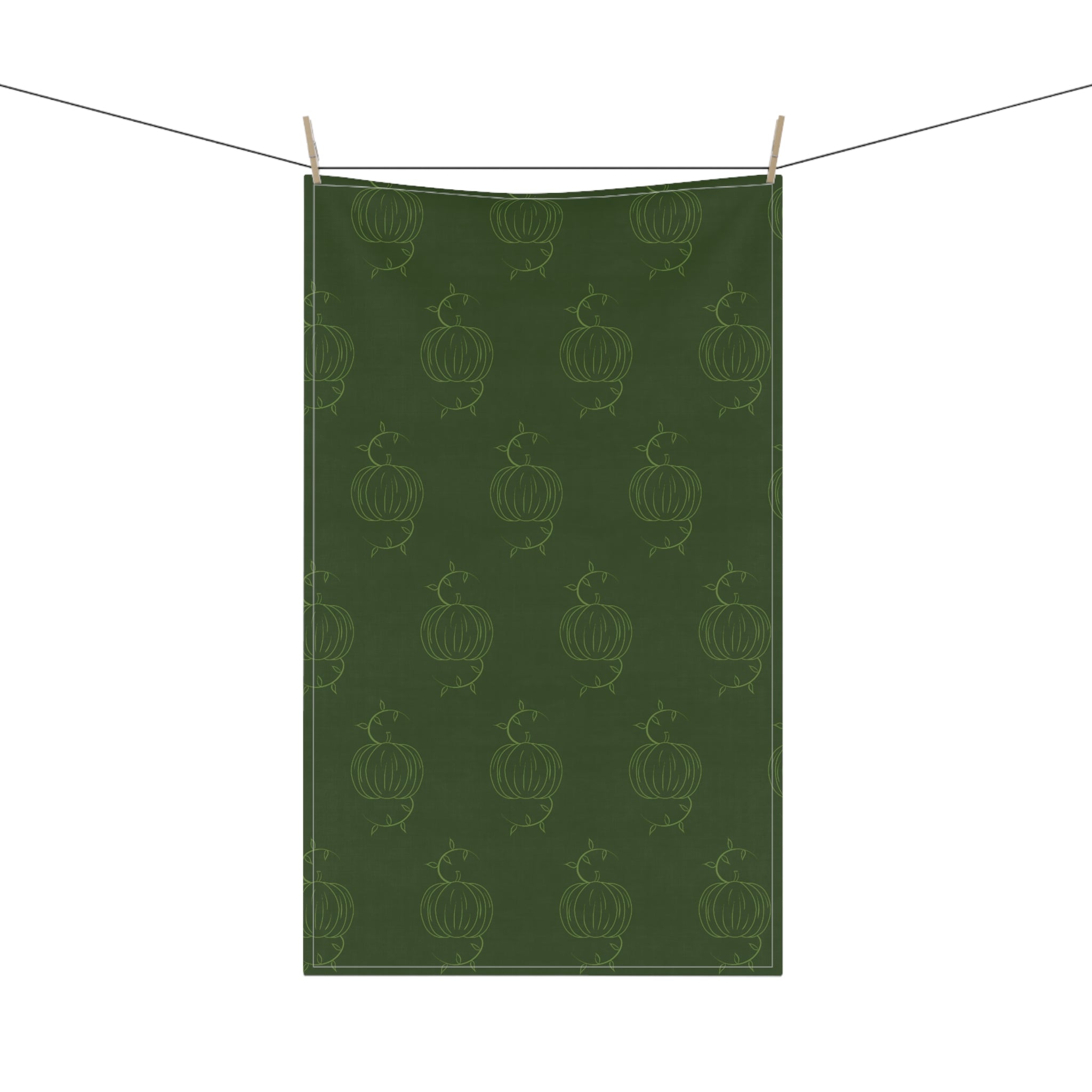 Hanging green tea towel with repeating pumpkin line pattern and clothespins
