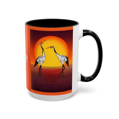 Orange coffee mug with origami crane sunset print and black handle, black rim.