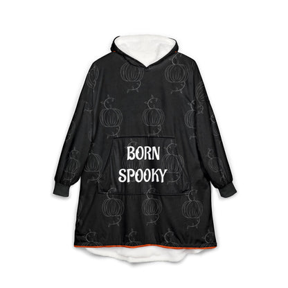 Black hooded blanket with pumpkin motif, front pocket, and "BORN SPOOKY" text